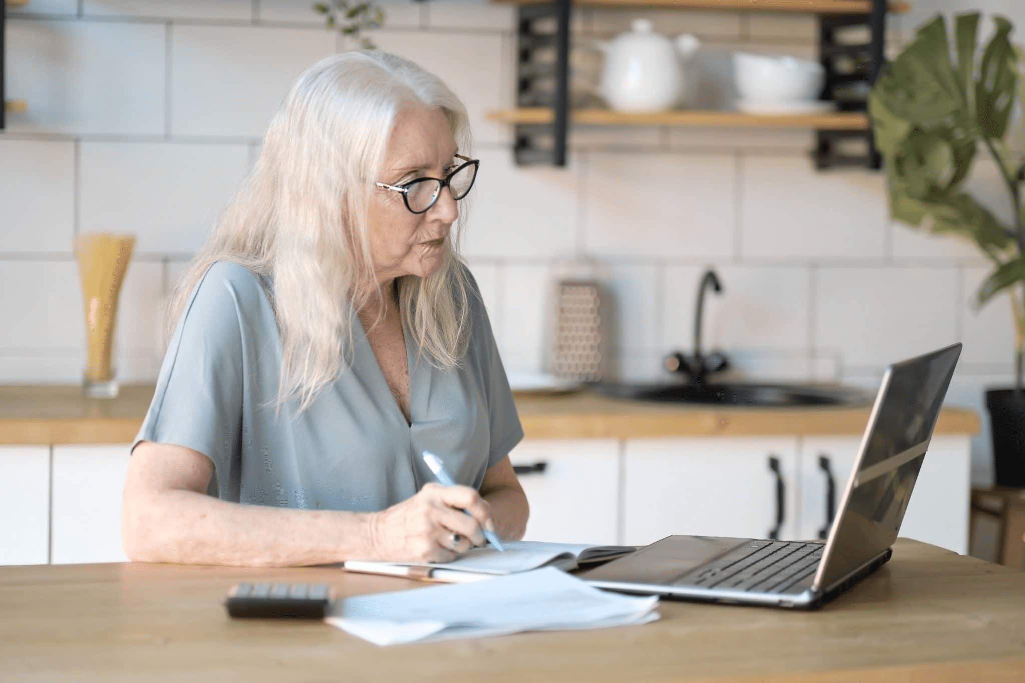 Eldre dame sitter foran pcen og noterer